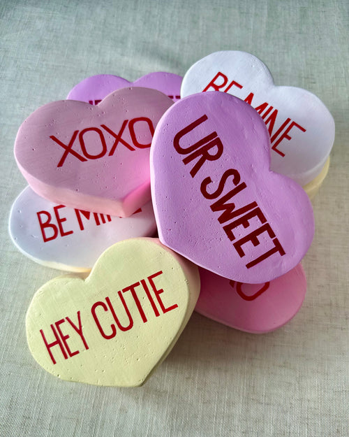 Heart-shaped conversation sculptures with Valentine's Day messages on a light background