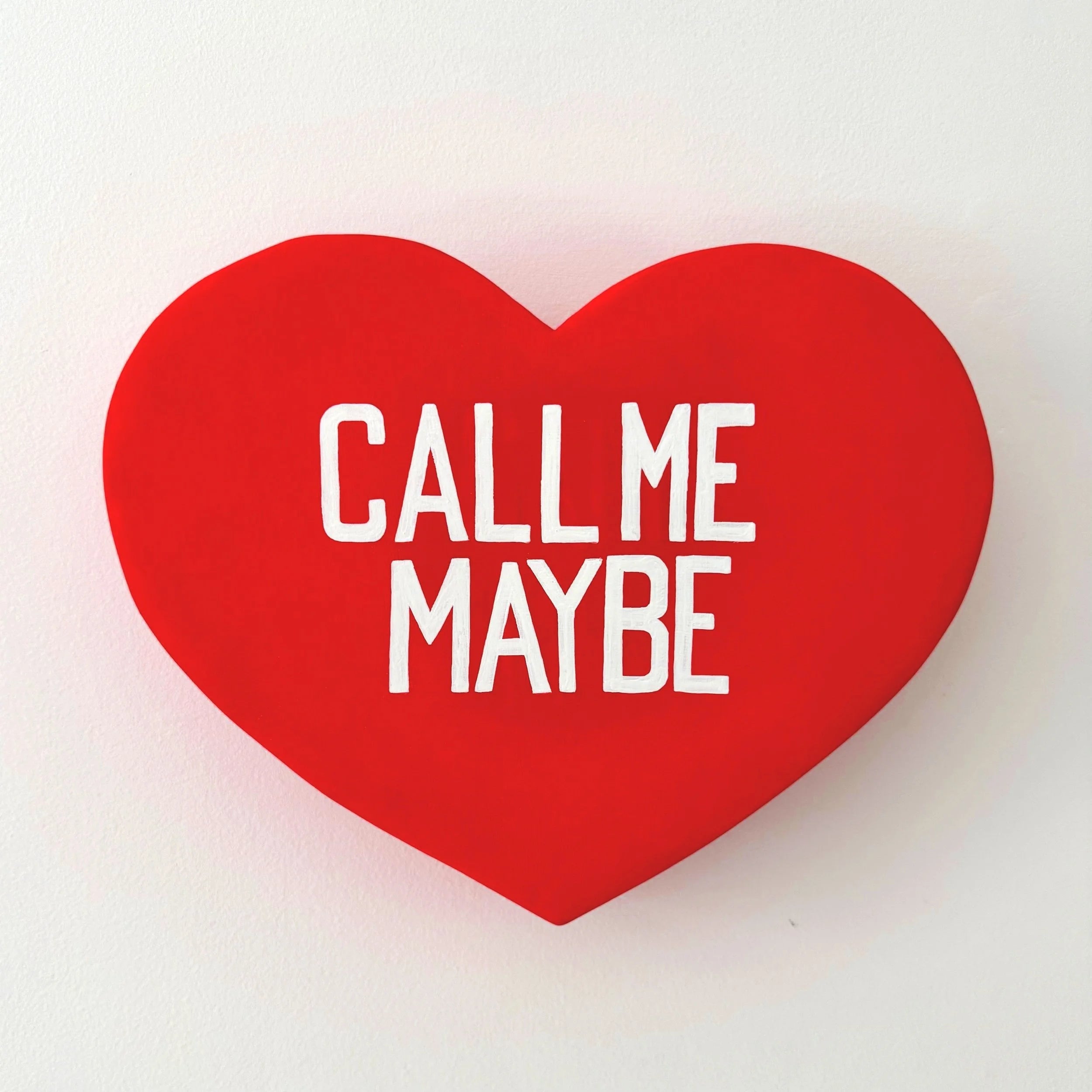 Red heart-shaped sculpture with 'Call Me Maybe' text on a white background