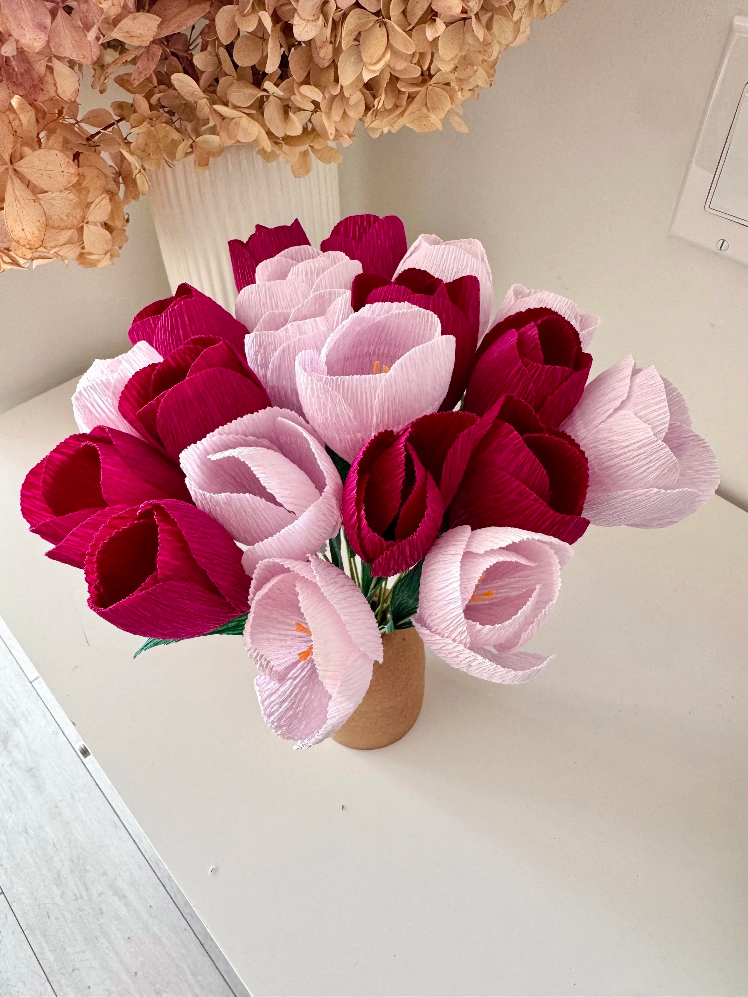 Bouquet of light and dark purple crocuses in a vase on a light surface.