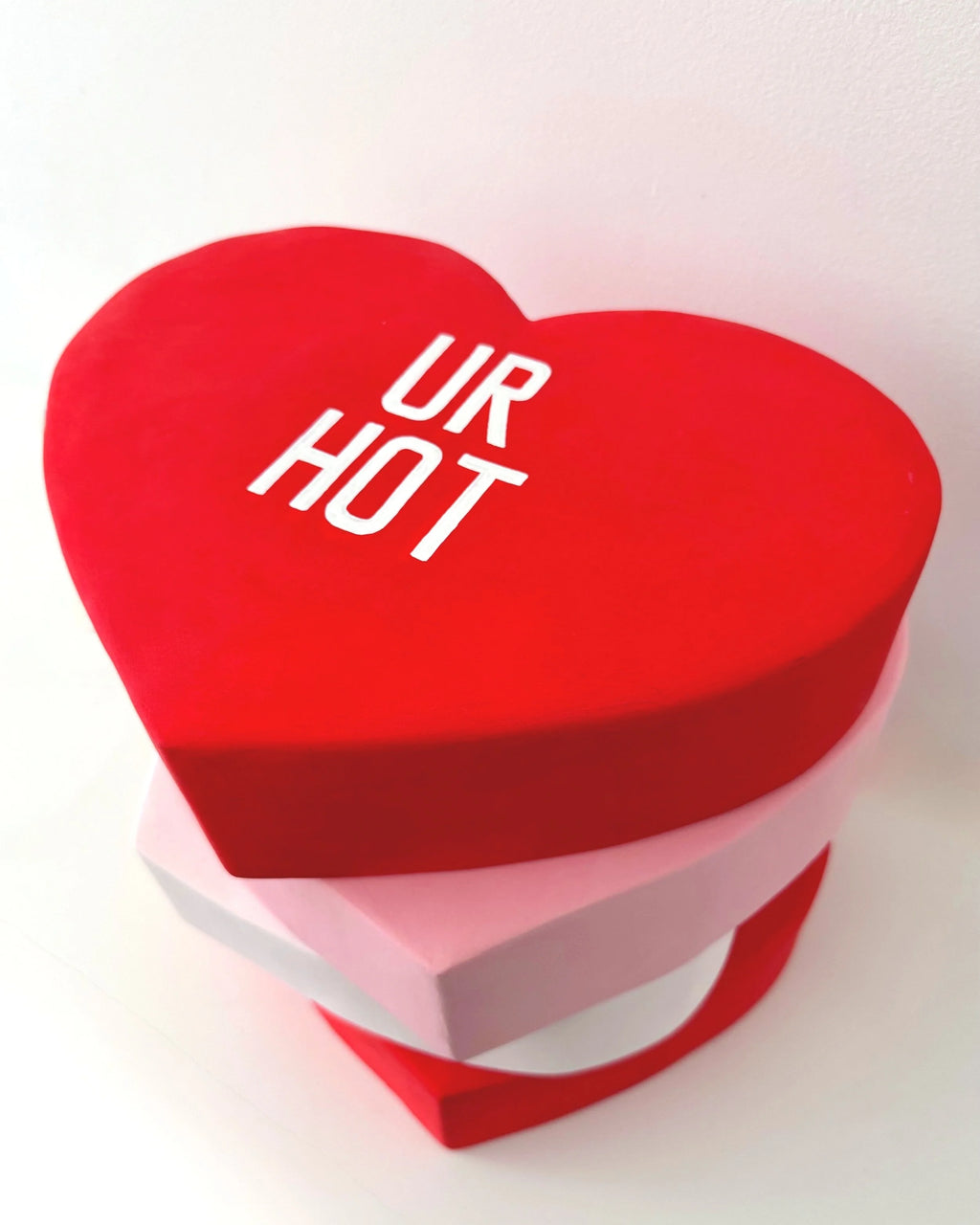 Heart-shaped red sculpture with 'UR HOT' text on a white background