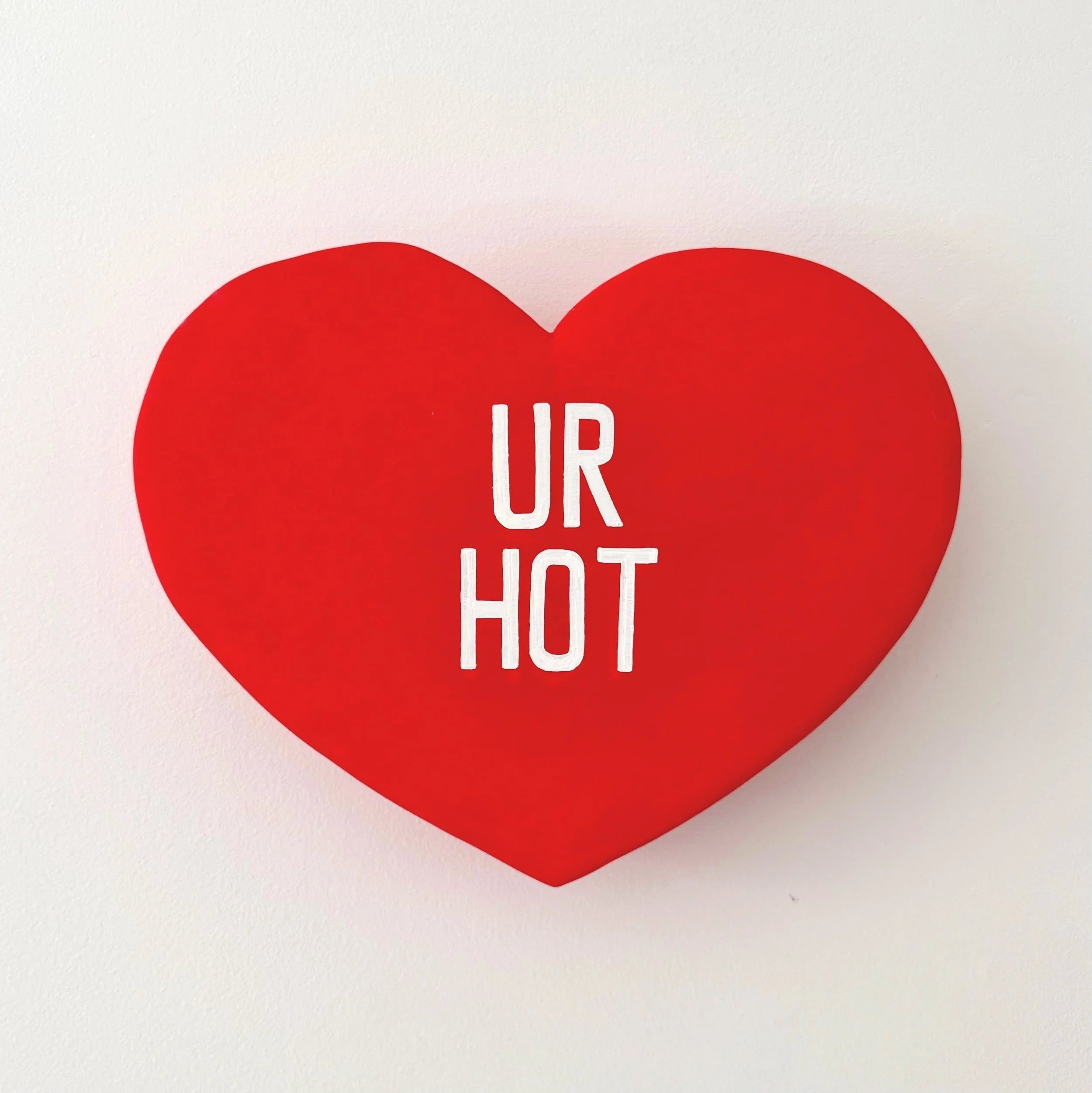 Red heart-shaped sculpture with 'UR HOT' text on a white background